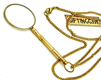 May include: A gold-toned magnifying glass necklace with a round lens and a chain. The magnifying glass has a retractable handle.