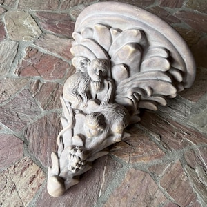May include: A beige-colored wall sculpture featuring a detailed relief of monkeys and foliage. The sculpture has a curved, layered design with a textured surface, and is mounted on a stone wall. The monkeys are depicted in a naturalistic style.