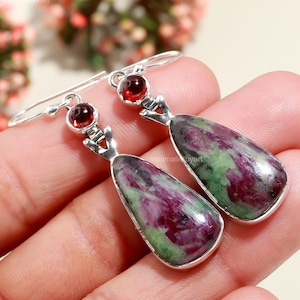 Pode incluir: Um par de brincos de prata com gotas de zoisita rubi verde e rosa e detalhes em granada vermelha.