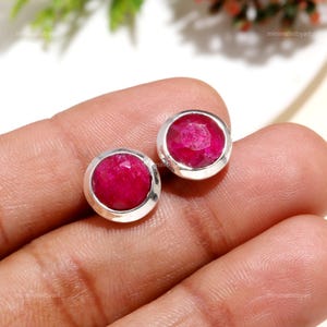 Puede incluir: Un par de pendientes de botón de plata con piedras redondas de rubí rojo.