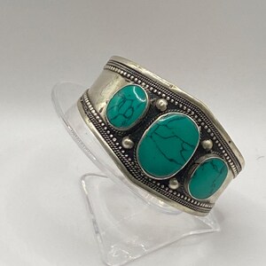 May include: Silver bracelet with three turquoise stones set in a decorative design.
