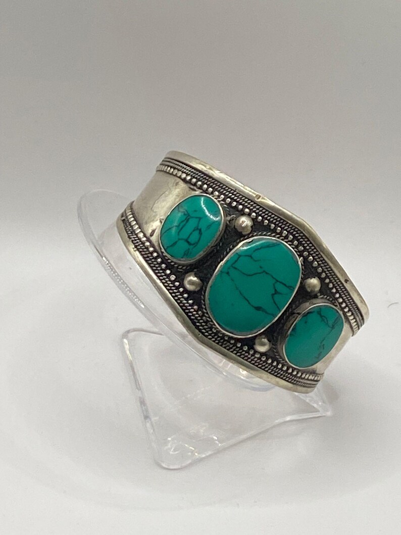 May include: Silver bracelet with three turquoise stones set in a decorative design.