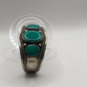 May include: Silver bracelet with three turquoise stones set in a decorative design.