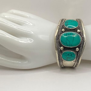 May include: Silver bracelet with three turquoise stones set in a decorative design.