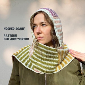 Könnte beinhalten: Ein Kapuzen-Schal mit einem gestreiften Muster in Grün, Weiß, Rosa und Gelb. Der Schal ist gestrickt und hat eine Kapuze. Der Text "HOODED SCARF PATTERN FOR ADDI/SENTRO" ist im Bild sichtbar.