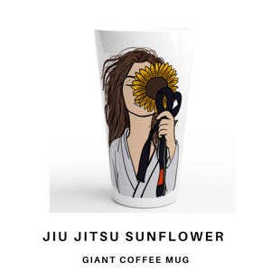 May include: Large white coffee mug with a graphic of a person with brown hair, a sunflower, and a black belt. The mug has the text "JIU JITSU SUNFLOWER" and "GIANT COFFEE MUG" in black.