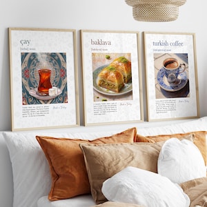 May include: Three framed prints featuring Turkish cuisine. The first shows a glass of tea, the second baklava, and the third Turkish coffee. Each print has a beige frame and includes text describing the food or drink. The prints are displayed above a bed with pillows.