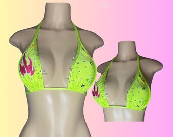 May include: Neon green bikini set with a halter top and string bottom. The bikini top features a pink flame design and is embellished with silver accents. The text "Glittergyal" is displayed in a retro font.