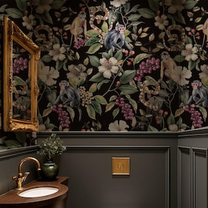 Könnte beinhalten: Ein Gäste-WC mit dunkler floraler Tapete mit Affen, Blumen und Ranken. Der Raum hat eine dunkelgraue Täfelung, ein Waschbecken aus Holz mit goldenen Armaturen, eine weiße Toilette und einen goldgerahmten Spiegel. Der Boden ist aus Holz.