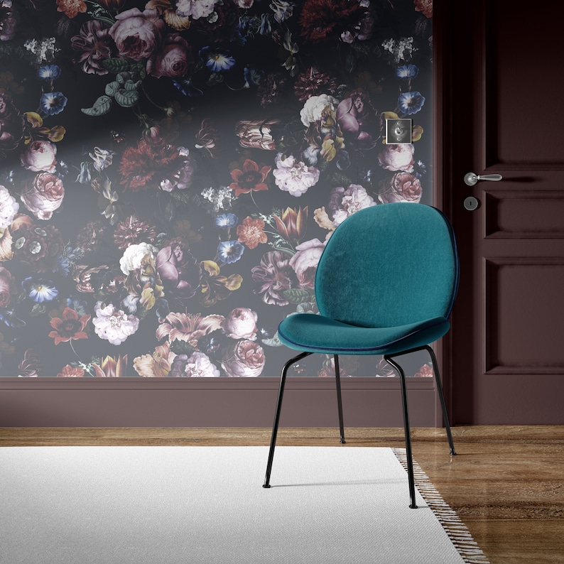 May include: A teal velvet chair with black metal legs sits in front of a dark floral wallpaper. The chair has a rounded back and a slightly curved seat.