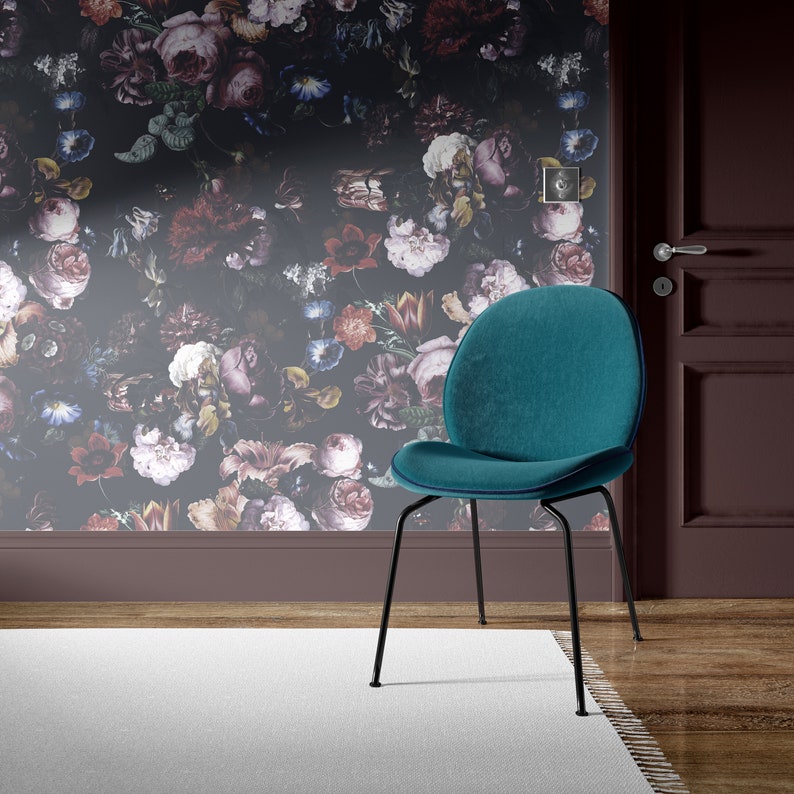 May include: A teal velvet chair with black metal legs sits in front of a wall with a dark floral wallpaper pattern.