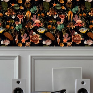 May include: A black and white wallpaper with a repeating pattern of sea life, including fish, seahorses, starfish, seashells, and coral. The wallpaper is displayed on a white wall with a record player and two white speakers on a wooden shelf.