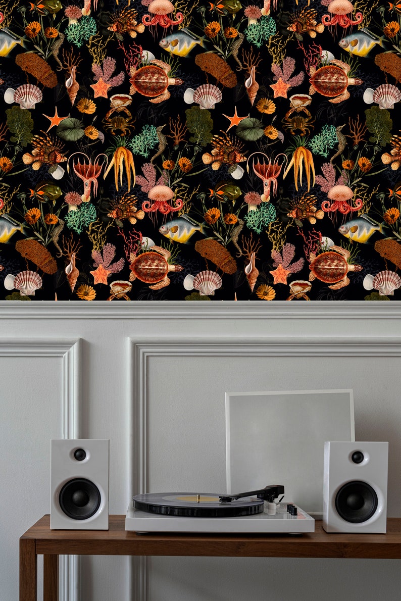 May include: A black and white wallpaper with a repeating pattern of sea life, including fish, seahorses, starfish, seashells, and coral. The wallpaper is displayed on a white wall with a record player and two white speakers on a wooden shelf.
