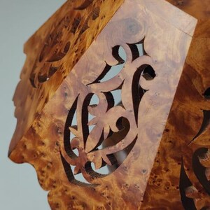 May include: A wooden decorative box with intricate cut-out designs. The box is made of a warm-toned wood with a natural grain pattern. The cut-out patterns are ornate and add a touch of elegance to the piece.