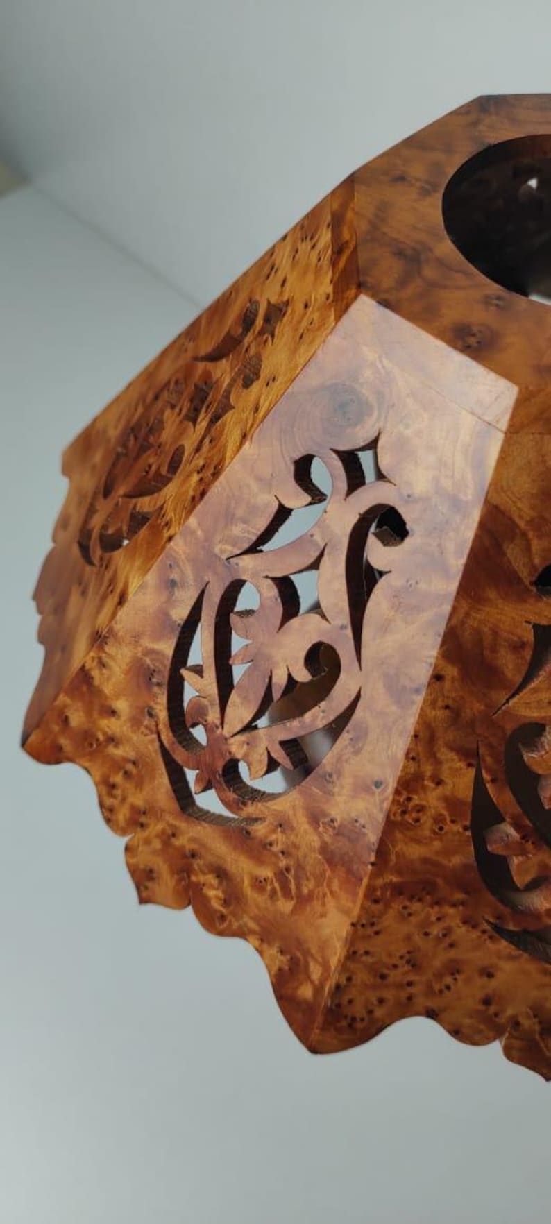 May include: A wooden decorative box with intricate cut-out designs. The box is made of a warm-toned wood with a natural grain pattern. The cut-out patterns are ornate and add a touch of elegance to the piece.
