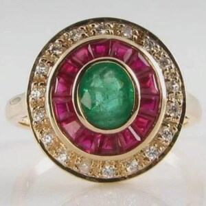 Puede incluir: Un anillo de oro con una esmeralda verde central, rodeada de rubíes rojos y un halo de pequeños diamantes. El anillo presenta un diseño clásico y elegante.