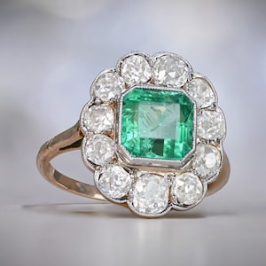 May include: A gold ring featuring a large emerald green gemstone surrounded by a halo of smaller diamonds.