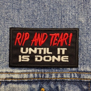 Peut inclure: Patch brodé noir et blanc avec du texte rouge qui dit "Rip and Tear! Until it is done".