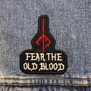 May include: Black and white embroidered patch with a red symbol and the text "FEAR THE OLD BLOOD".