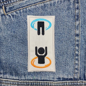 May include: Embroidered patch showing a black stick figure falling through an orange portal, with another stick figure falling from a blue portal above. The patch is on a blue denim jacket.