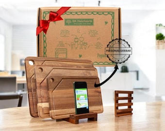 May include: A set of wooden cutting boards in various sizes, with a smartphone propped up on a wooden stand. The boards are displayed with a gift box tied with a red bow. The box has the text "SK Holzfabrik" and a "Personalizable" badge.
