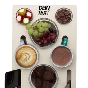 May include: A wooden serving board with various food items arranged in small bowls. Includes grapes, cookies, coffee, and stuffed peppers. The text "DEIN TEXT" is printed at the top. The board has a modern design.