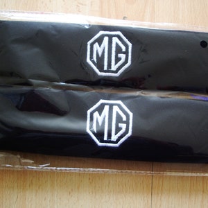 A pair of beautifully embroidered MG seat belt covers