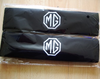 A pair of beautifully embroidered MG seat belt covers