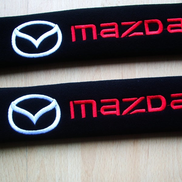 A pair of beautifully embroidered Mazda soft seat belt covers