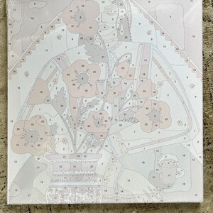 May include: A paint-by-numbers canvas featuring a floral still life. The design includes a vase of flowers with a woman's face in the background. The color palette is soft, with shades of pink, beige, and gray. The canvas is wrapped in clear plastic.