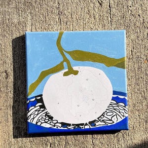 May include: Square canvas art depicting a white fruit with a green stem and leaves against a light blue backdrop. The fruit has numbers for paint-by-number. The bottom border has a blue and white patterned design.