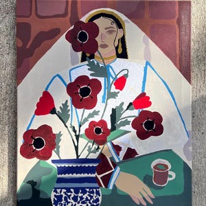 May include: An original painting featuring a woman in white attire with red poppies in a blue and white vase. A cup of coffee sits on a green surface. The background includes a brick-like pattern.