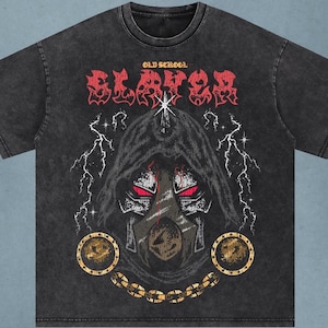 Puede incluir: Camiseta gris oscuro con un gráfico de una figura encapuchada con ojos rojos, rayos y la palabra "SLAYER" en rojo. El texto "OLD SCHOOL" está encima del gráfico. Una cadena dorada con colgantes circulares está en la parte inferior.