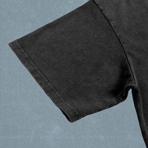 A close-up view of a dark grey t-shirt against a blue background.
