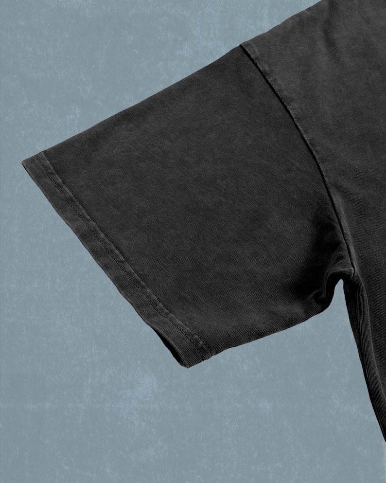 A close-up view of a dark grey t-shirt against a blue background.
