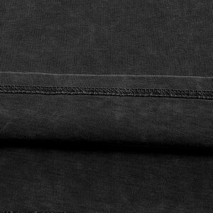The image is a close-up of a black fabric, possibly a piece of clothing or a textile. The fabric appears to be wrinkled and has a textured surface.