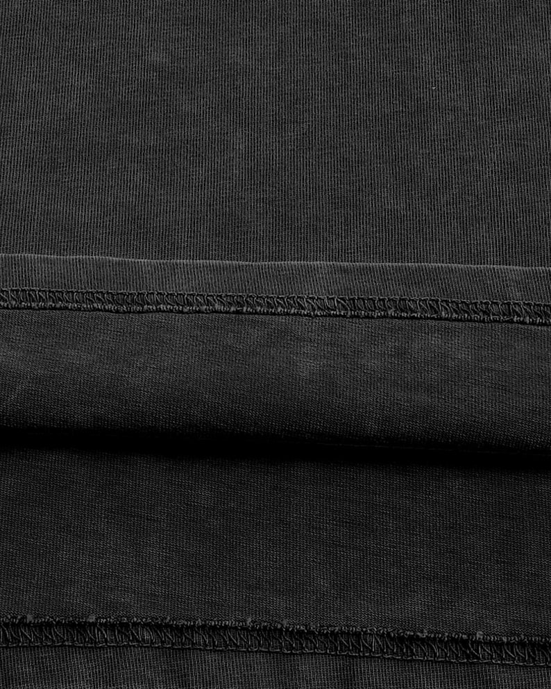 The image is a close-up of a black fabric, possibly a piece of clothing or a textile. The fabric appears to be wrinkled and has a textured surface.