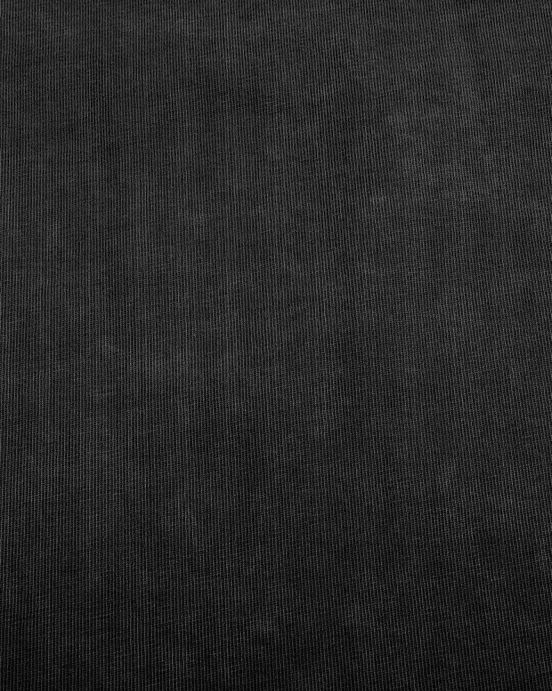 The image is a close-up of a black fabric with a textured appearance.