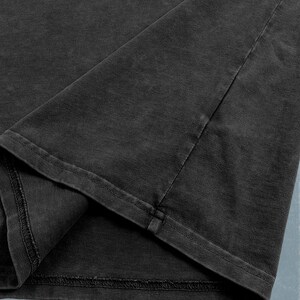 A close-up view of a dark grey fabric, possibly a piece of clothing or a textile.