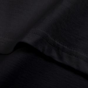 Op de afbeelding: Close-up van zwarte t-shirtstof, met de textuur en stiksels. De tekst onderaan luidt: "Soft Cotton Feel Lightweight 230GSM 100% cotton with a smooth finish."