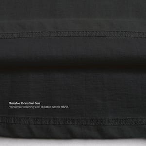 Op de afbeelding: Close-up van een donkergrijze stof met zichtbare stiksels. De tekst "Durable Construction" en "Reinforced stitching with durable cotton fabric" is op de stof gedrukt. De afbeelding benadrukt de constructie van het kledingstuk.