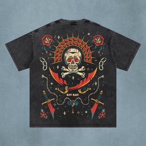Pode incluir: Uma t-shirt preta com efeito de lavagem ácida, apresentando uma estampa gráfica de um crânio sobre ossos cruzados, ladeado por duas rosas vermelhas e duas espadas curvas. O design inclui uma teia de aranha, correntes e o texto SIT-RAT.