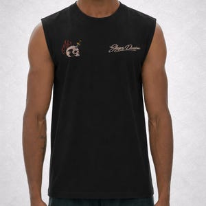 Op de afbeelding: Zwart mouwloos shirt met een schedelafbeelding doorboord door een dolk en de woorden "Slayer Division" in een cursief lettertype. De schedel is omgeven door vlammen. Het shirt is gemaakt van een zacht materiaal.