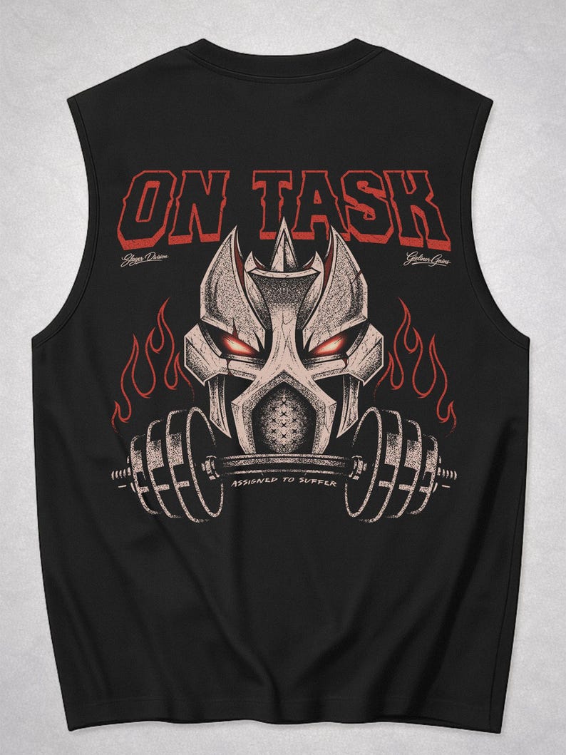 Op de afbeelding: Zwart mouwloos shirt met een grafisch ontwerp. Het ontwerp toont een gestileerde robothoofd met rode ogen die een halter vasthoudt, met vlammen en de tekst "ON TASK" in het rood. Onder de halter staat de tekst "ASSIGNED TO SUFFER".