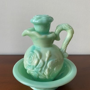 Könnte beinhalten: Eine antike grüne Glasflasche mit Rosenmuster und einer passenden Schale. Die Flasche hat einen Stopfen in Form einer Rose.