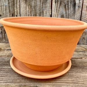 May include: A white ceramic mug with a black handle and the text "But First, Coffee" in a handwritten style. The mug is on a white surface. The mug is 4 inches tall.