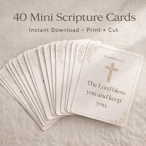 Może przedstawiać: Wachlarz 40 mini kart z Pismem Świętym z kwiatowymi akcentami. Karty są białe ze złotym tekstem i krzyżem. Tekst na karcie brzmi: „Niech Pan cię błogosławi i strzeże”.