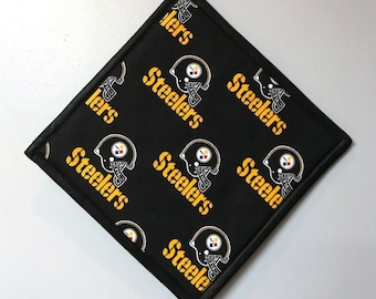 May include: Black square kitchen pot holder with a repeating pattern of yellow "Steelers" text and a black and white football helmet graphic.
