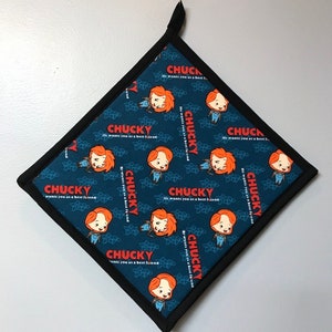 May include: A blue and black square pot holder with a repeating pattern of a cartoon character with red hair and the text "Chucky He wants you as a best friend".