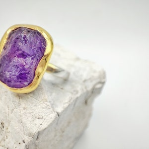 Lovely statement ring for glamorous outfits, featuring a brilliant natural raw amethyst gemstone, coated in 925 sterling silver, with a bezel setting of 18K gold. Minimal aesthetic with a medium, big natural purple amethyst gemstone ring.